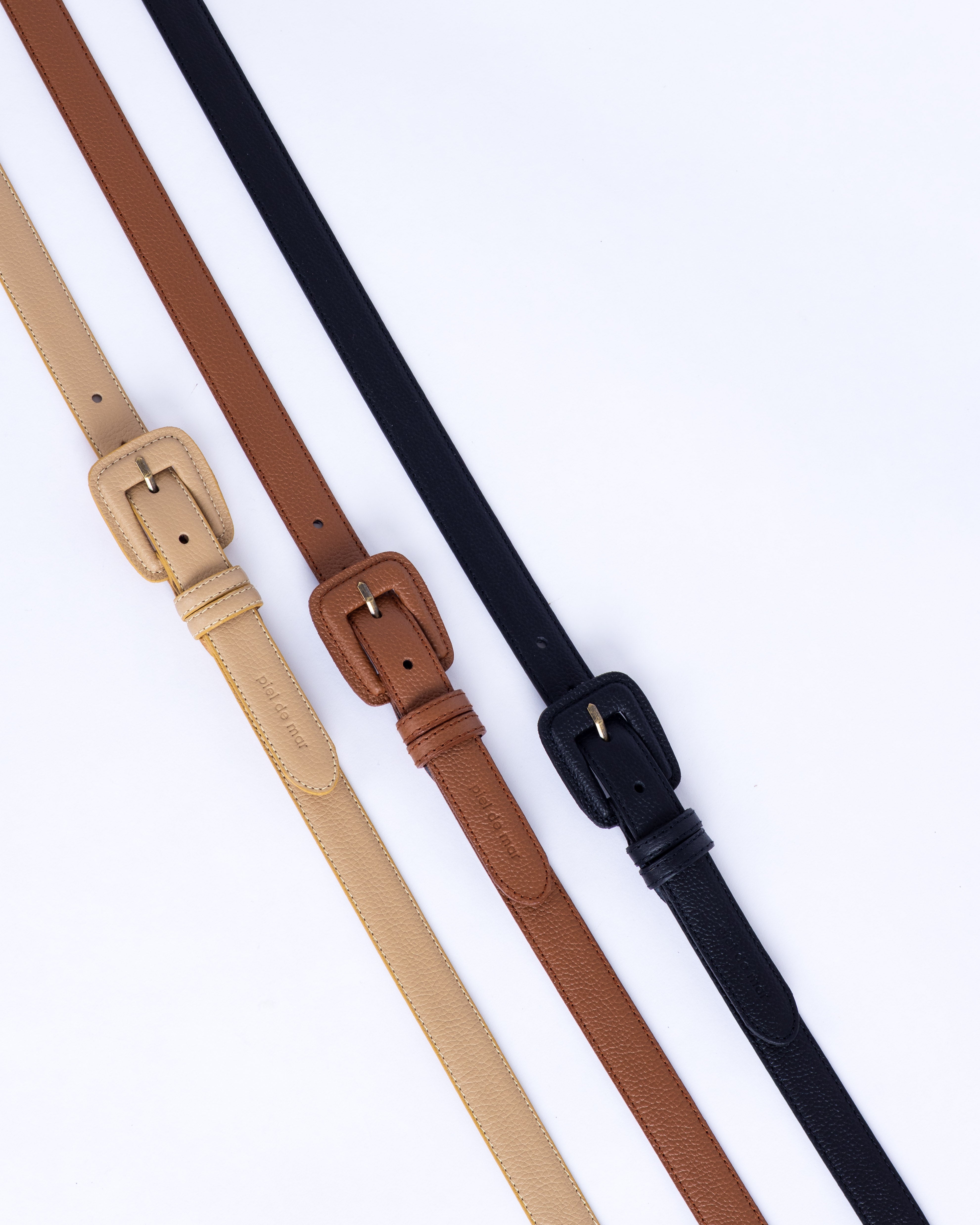 Beige, brown and black leather belts on a white background
